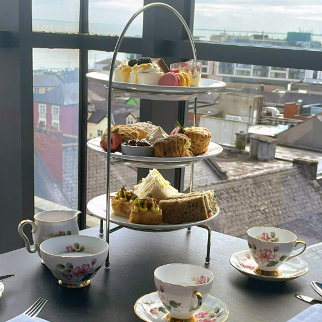 Afternoon tea try loaded with tasty treats served on delicate porcelain tea set at a table overlooking Wexford town and the Slaney estuary.