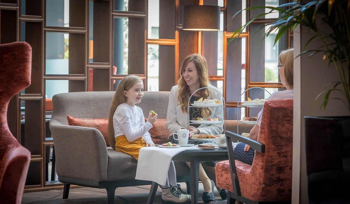 A young girl, her mother and grandmother sitting having afternoon tea in Whites of Wexford