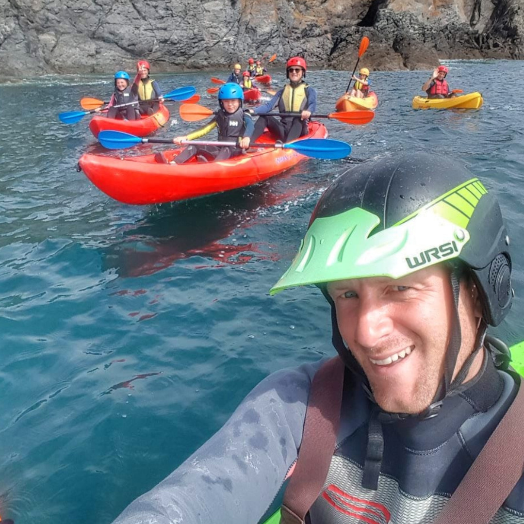 Graham from The Irish Experience taking a selfie with a family group kayaking in the calm blue sea off Baginbun head in the background on sunny summer day in Wexford