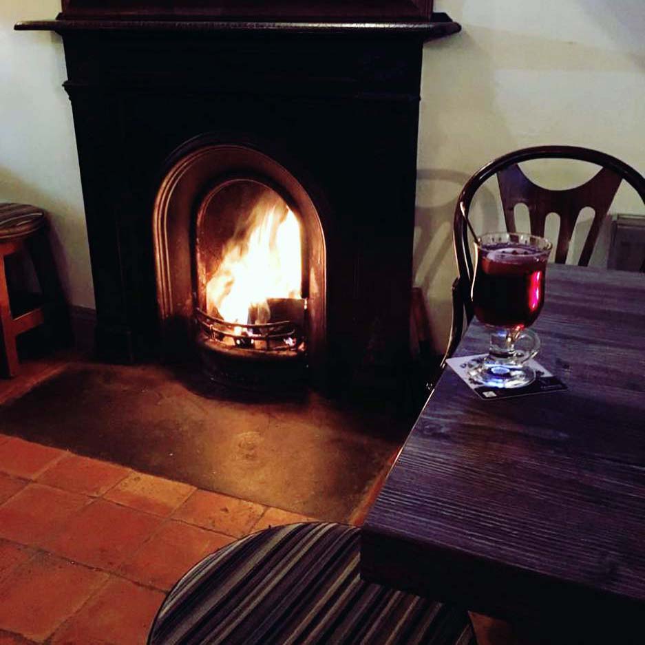 Cosy Open fire, hot drink  on the table and a stool at Vine Cottage Bar