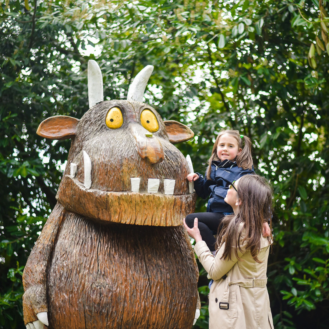 child on mom's should beside giant carving of the Gruffalo at Wells House and Gardens